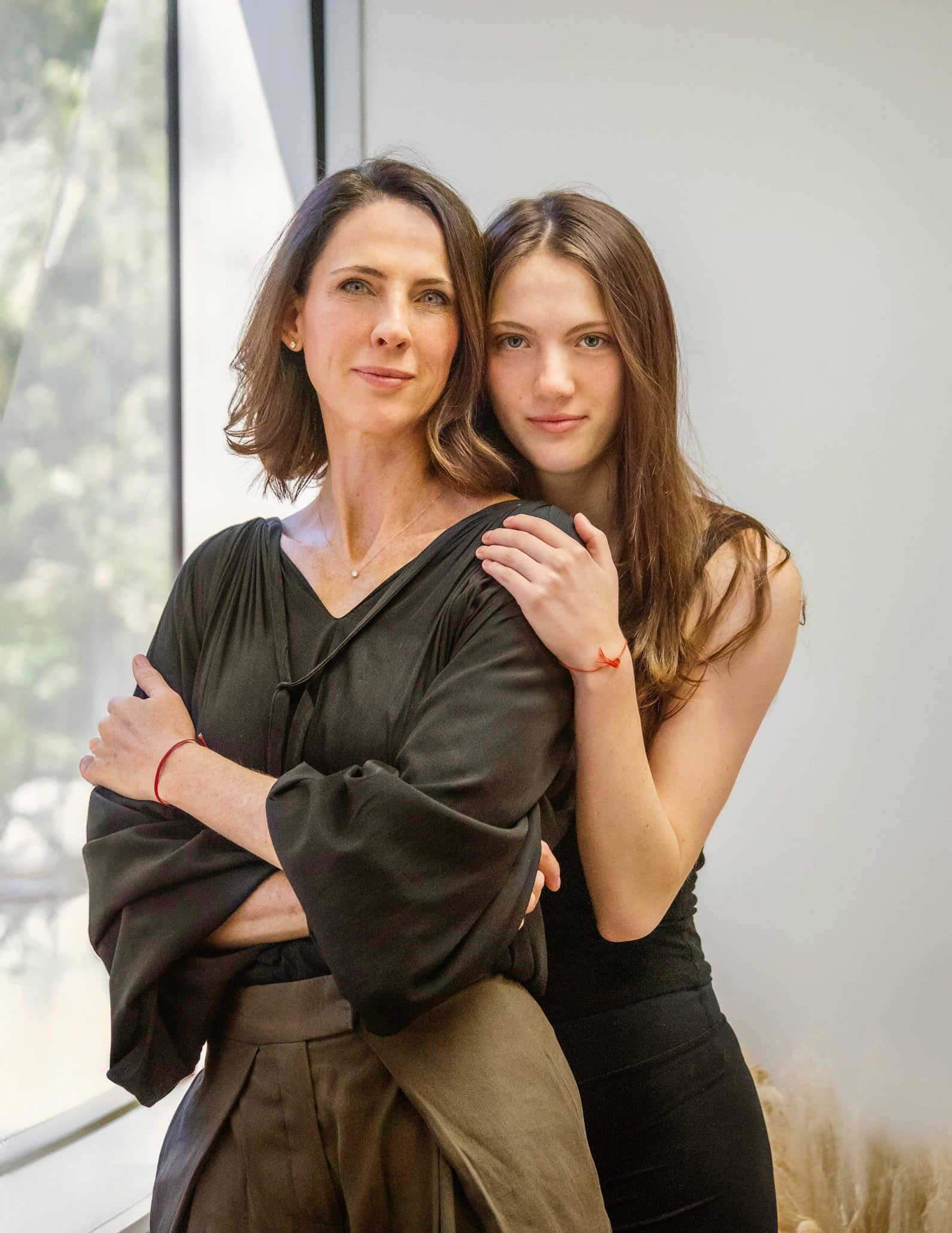 Two women standing together near window.