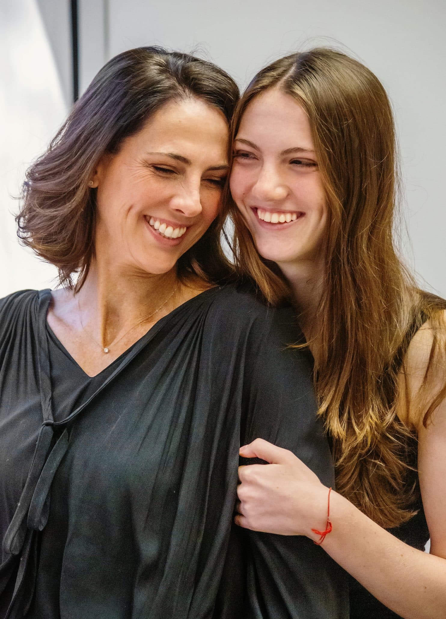 Mother and daughter smiling and hugging closely.