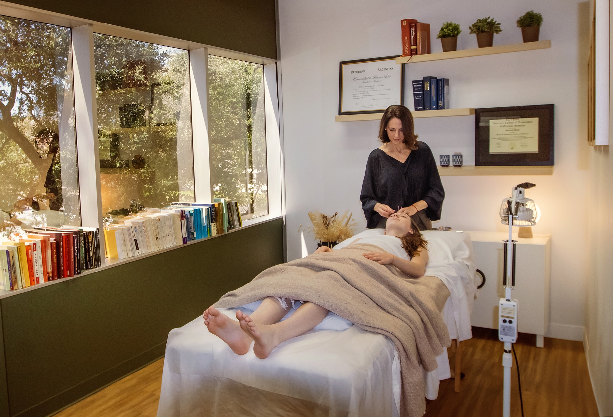 Acupuncturist treating patient in calm therapy room.