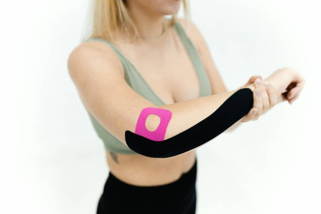 person with tape to elbow demonstrating support techniques for tennis elbow paining lateral epicondylitis treatment alongside acupuncture