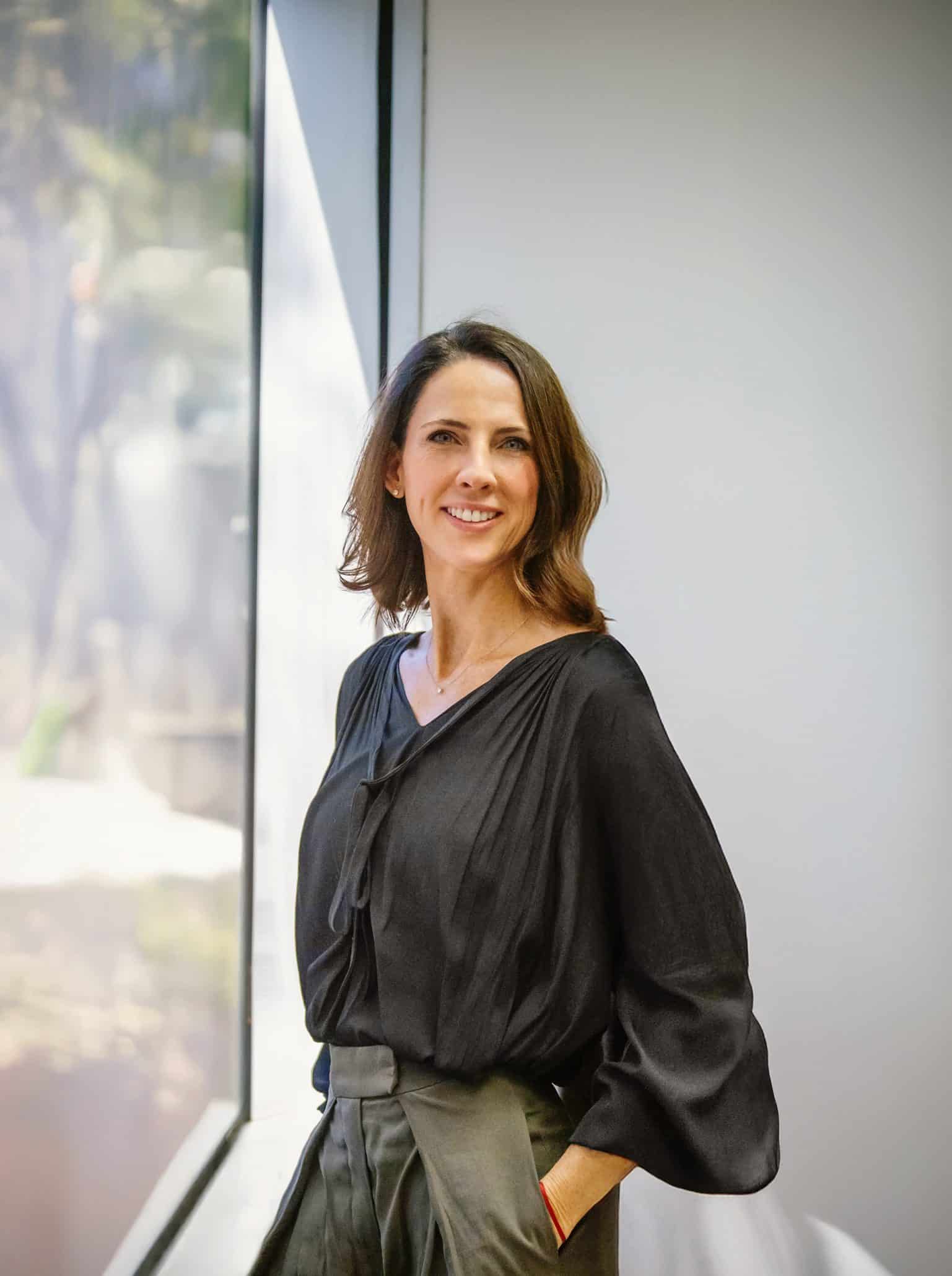 Smiling woman in black blouse by window