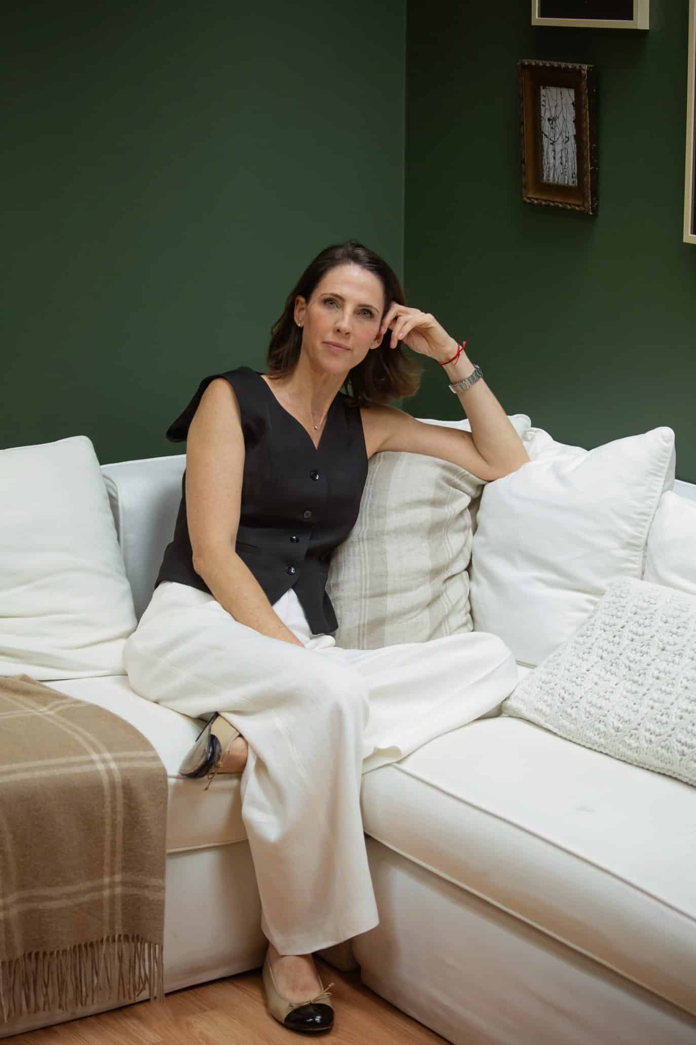 Woman relaxing on white couch with green wall.