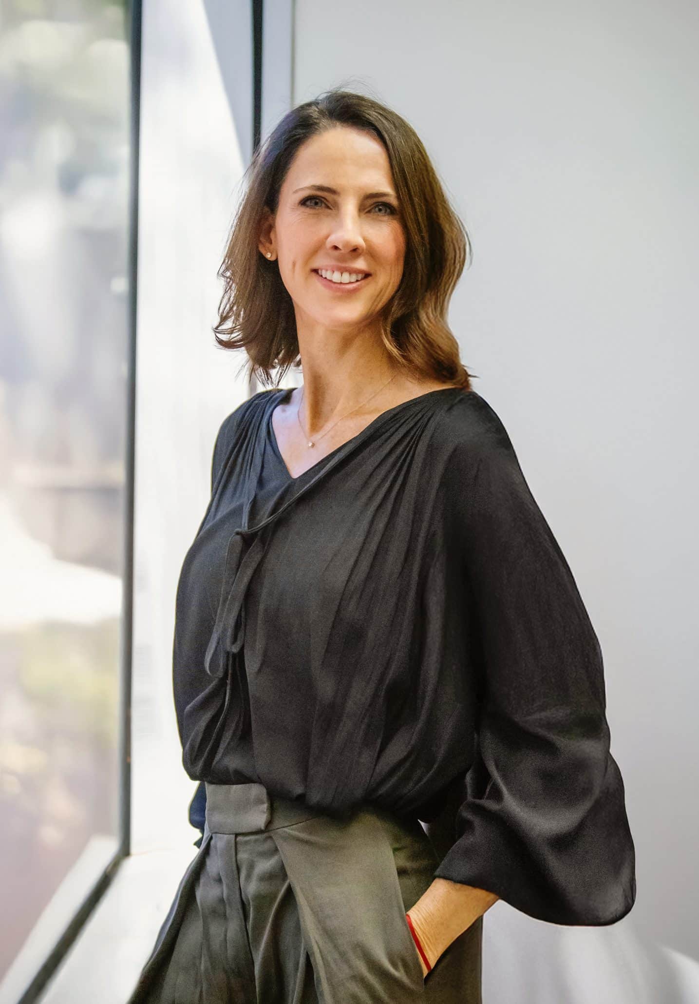 Smiling woman in black blouse by window
