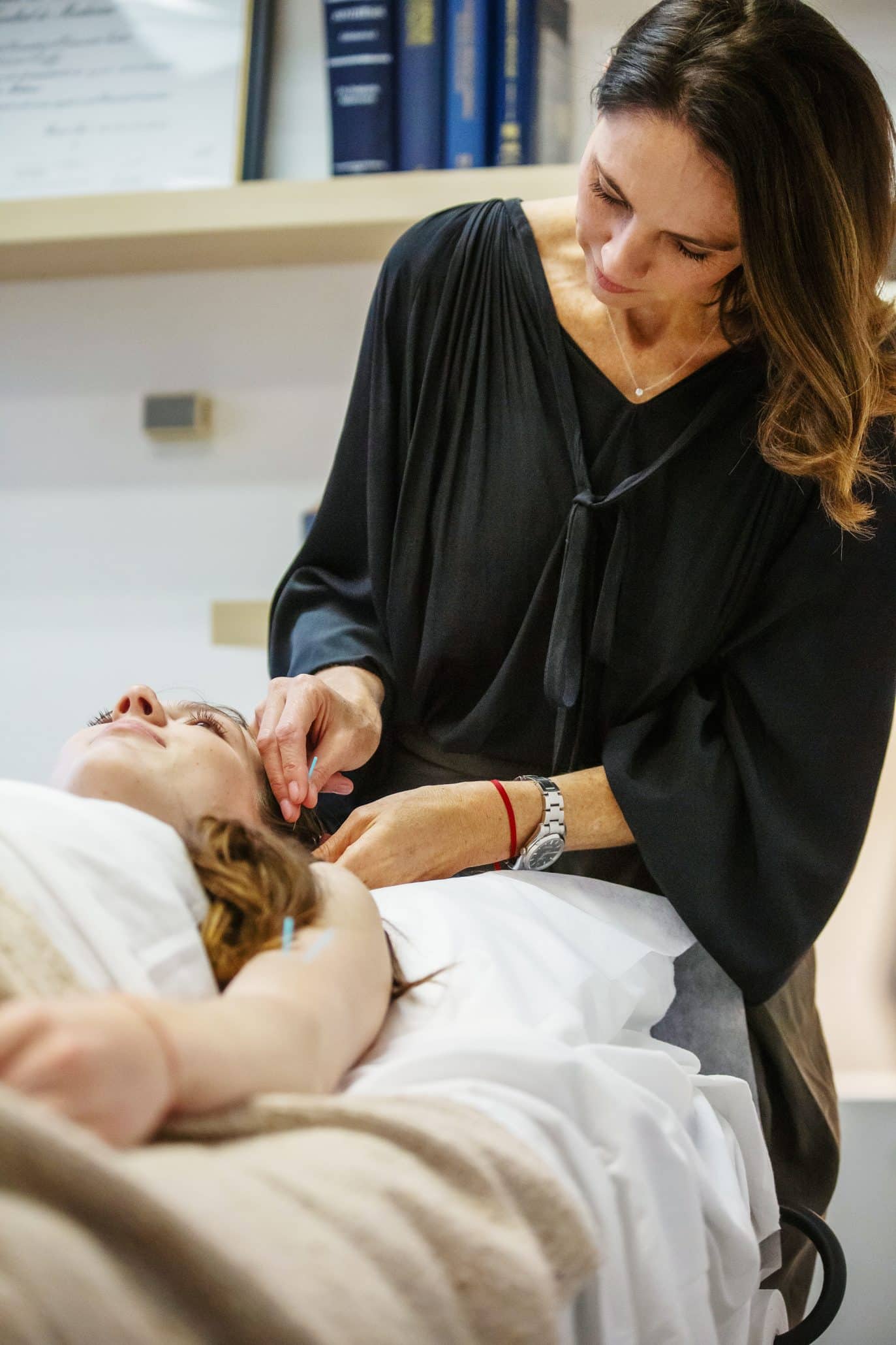 Woman performing acupuncture on client in spa.