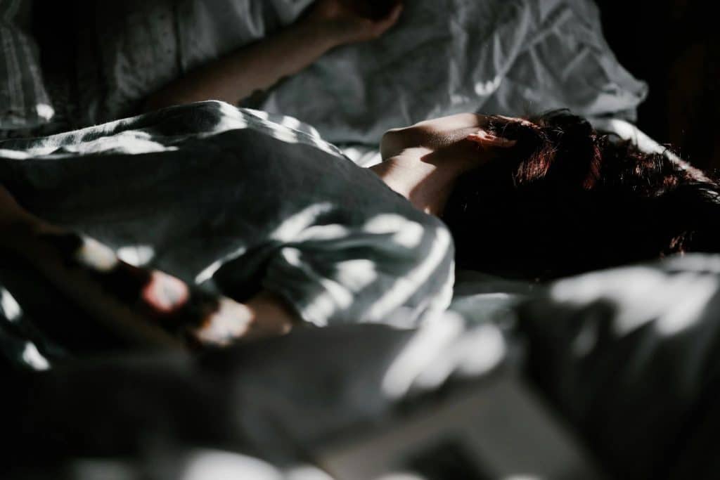 Person sleeping in dappled light on bed
